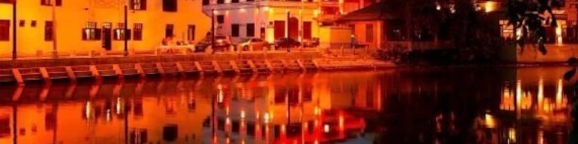 Un muelle con edificios iluminados que se reflejan en el agua al anochecer.