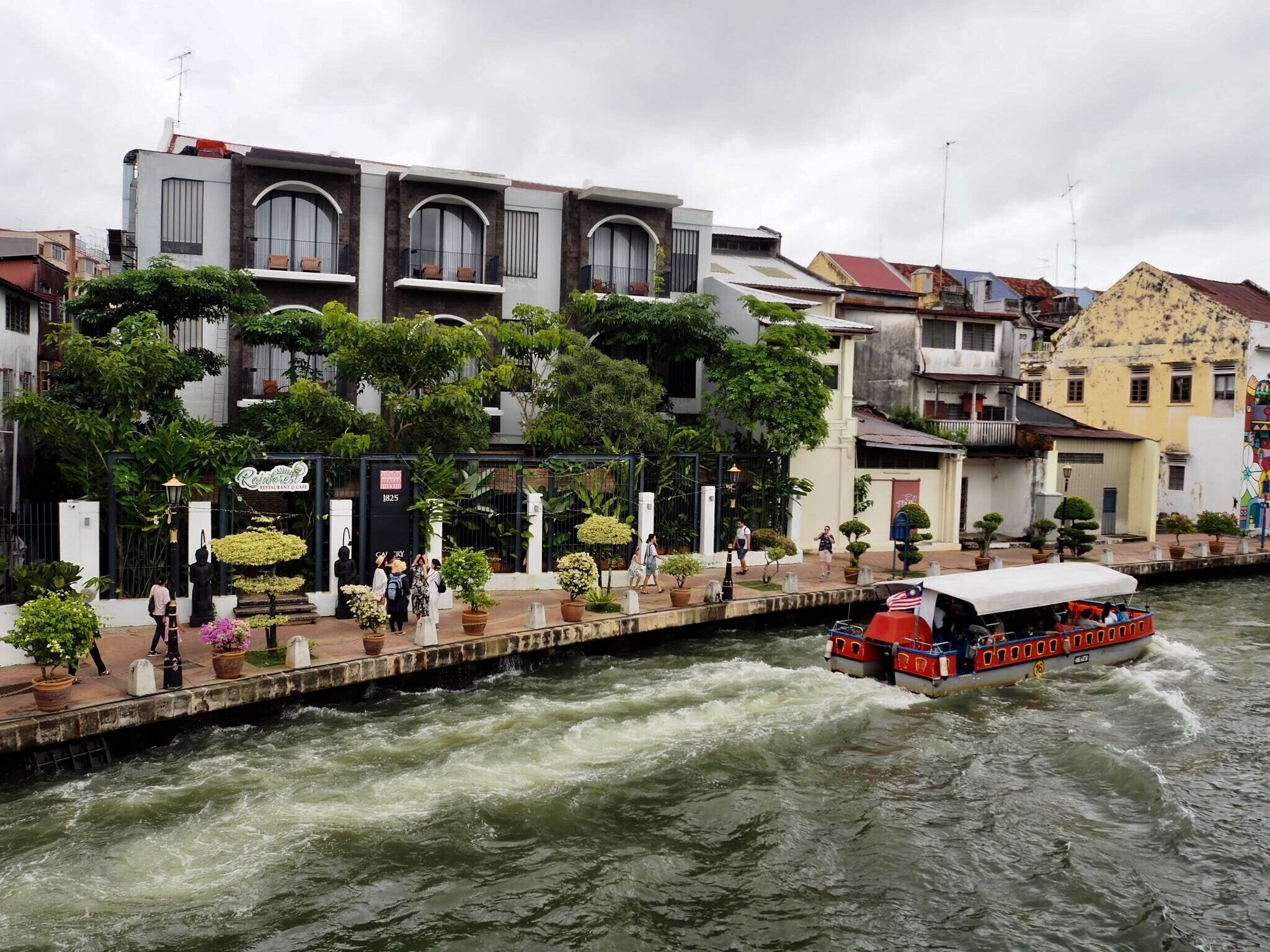 A river with a boat, a restaurant, and buildings along the riverbank.
