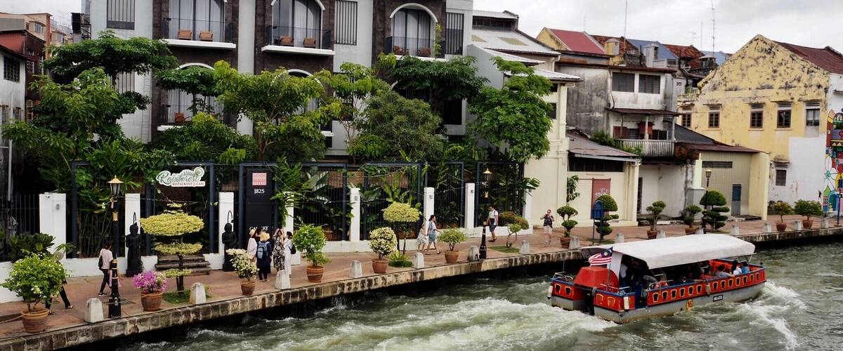 A river with a boat, a restaurant, and buildings along the riverbank.