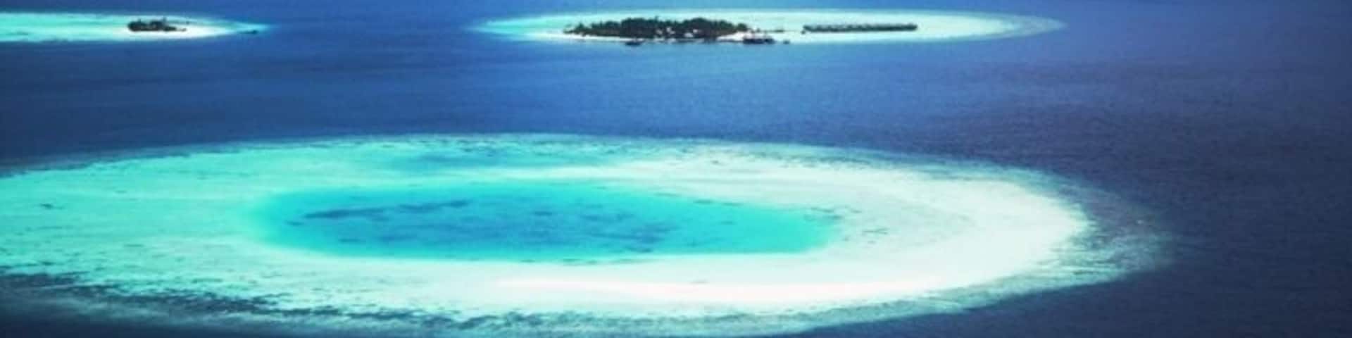 A turquoise lagoon surrounded by a coral reef, with small islands in the distance.