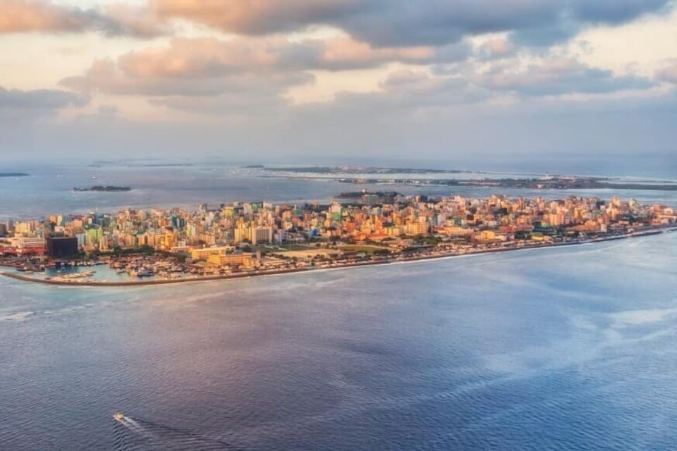 Vue aérienne d’une ville côtière, avec une zone urbaine densément peuplée et une longue péninsule s’étendant dans la mer.