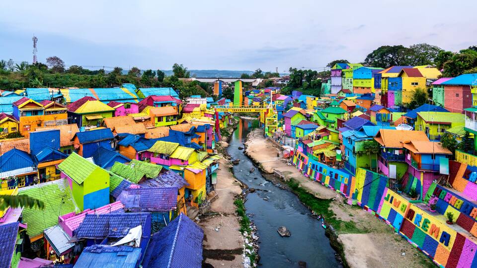 Een dichtbevolkt dorp met kleurrijke huizen en een rivier die erdoorheen kronkelt.