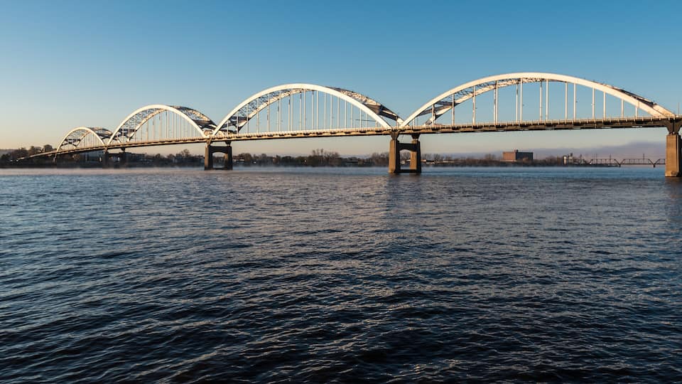A large, arched bridge spanning a river with calm water.
