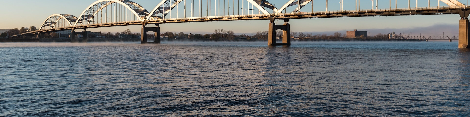 A large, arched bridge spanning a river with calm water.