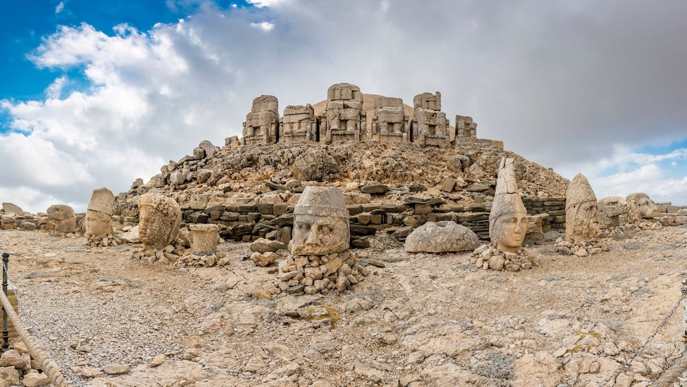 Ancient ruins with stone structures and scattered stones on a rocky terrain.