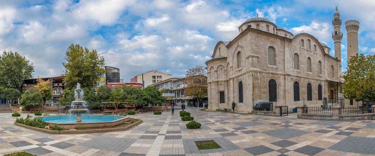 A historic building with a fountain and a mosque nearby.