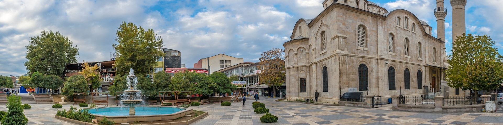 A historic building with a fountain and a mosque nearby.