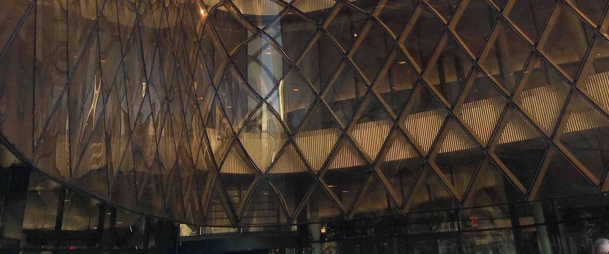 A modern architectural structure with a reflective glass facade and a unique, curved design.