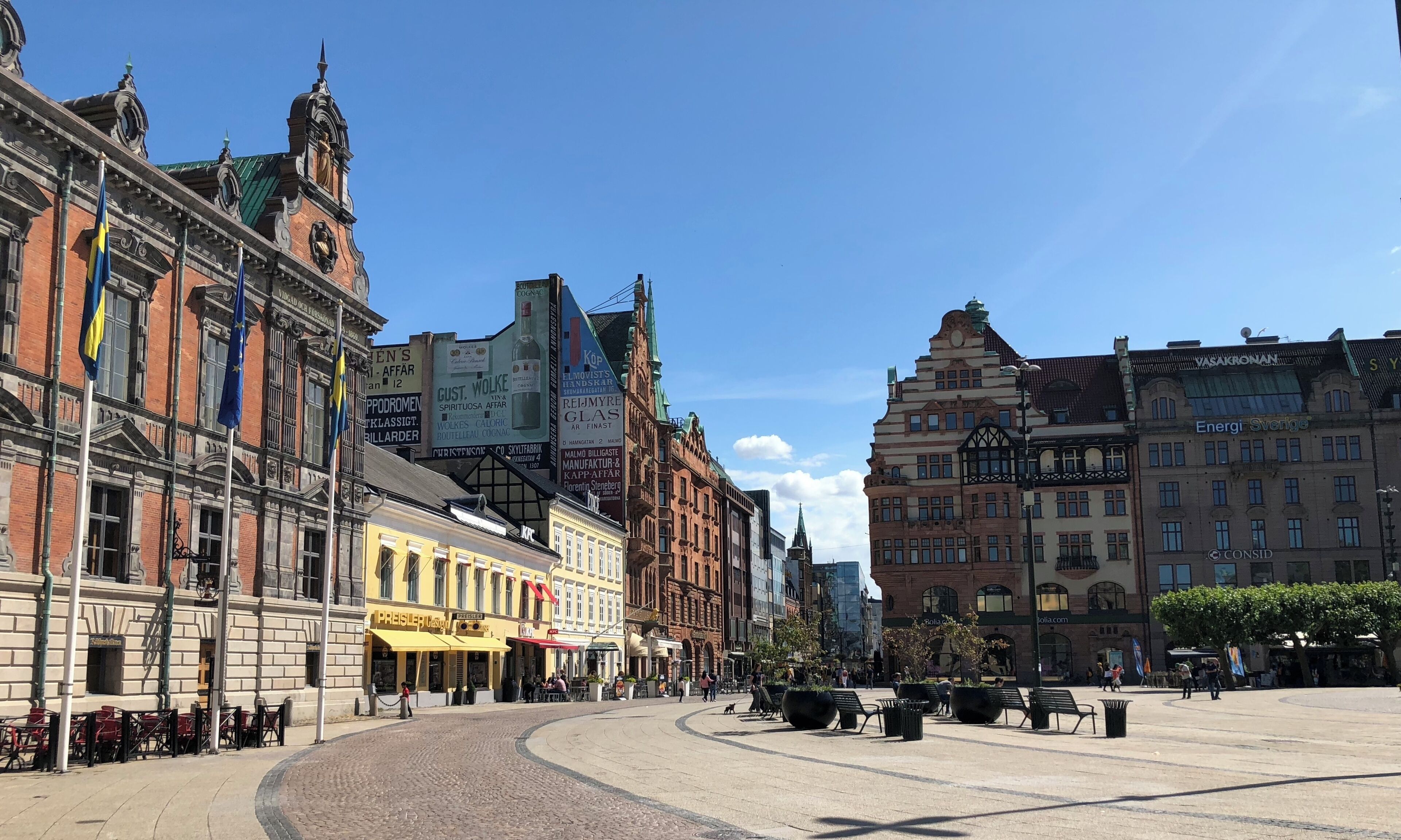 A historic European square with cobblestone pavement, traditional architecture, and outdoor seating areas.