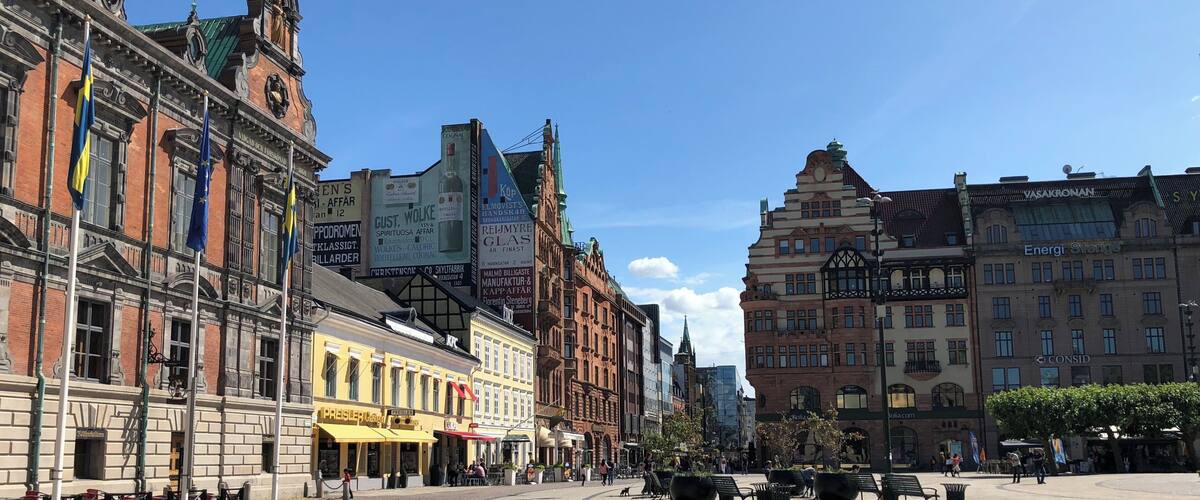 A historic European square with cobblestone pavement, traditional architecture, and outdoor seating areas.