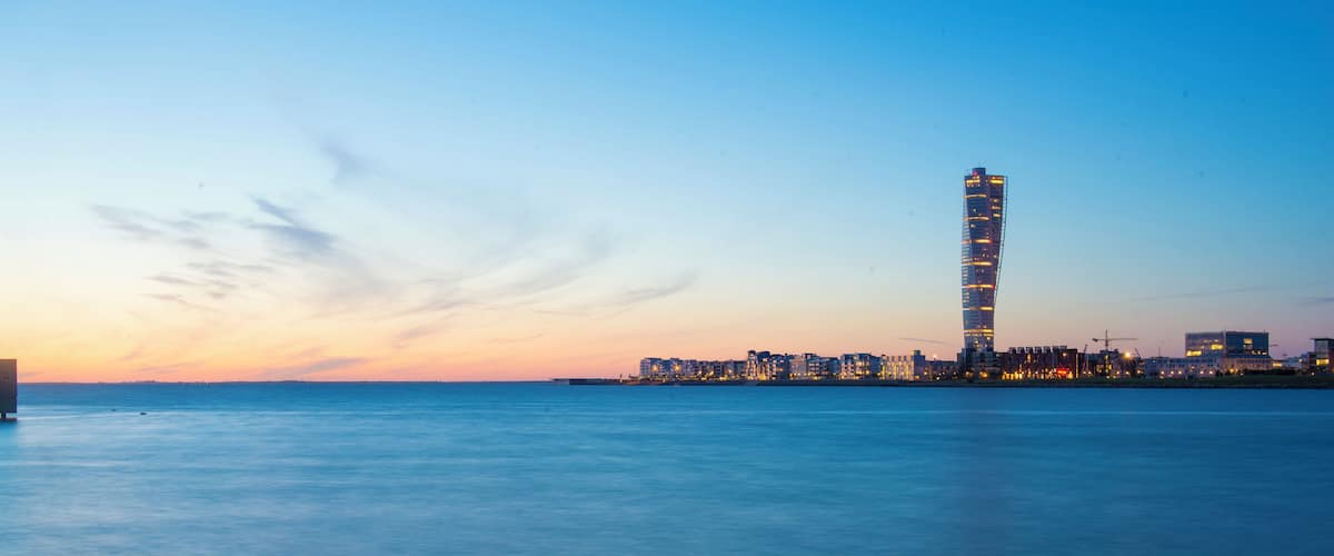 Malmö's Turning Torso skyscraper at sunset, overlooking calm waters in Skåne County, Sweden.