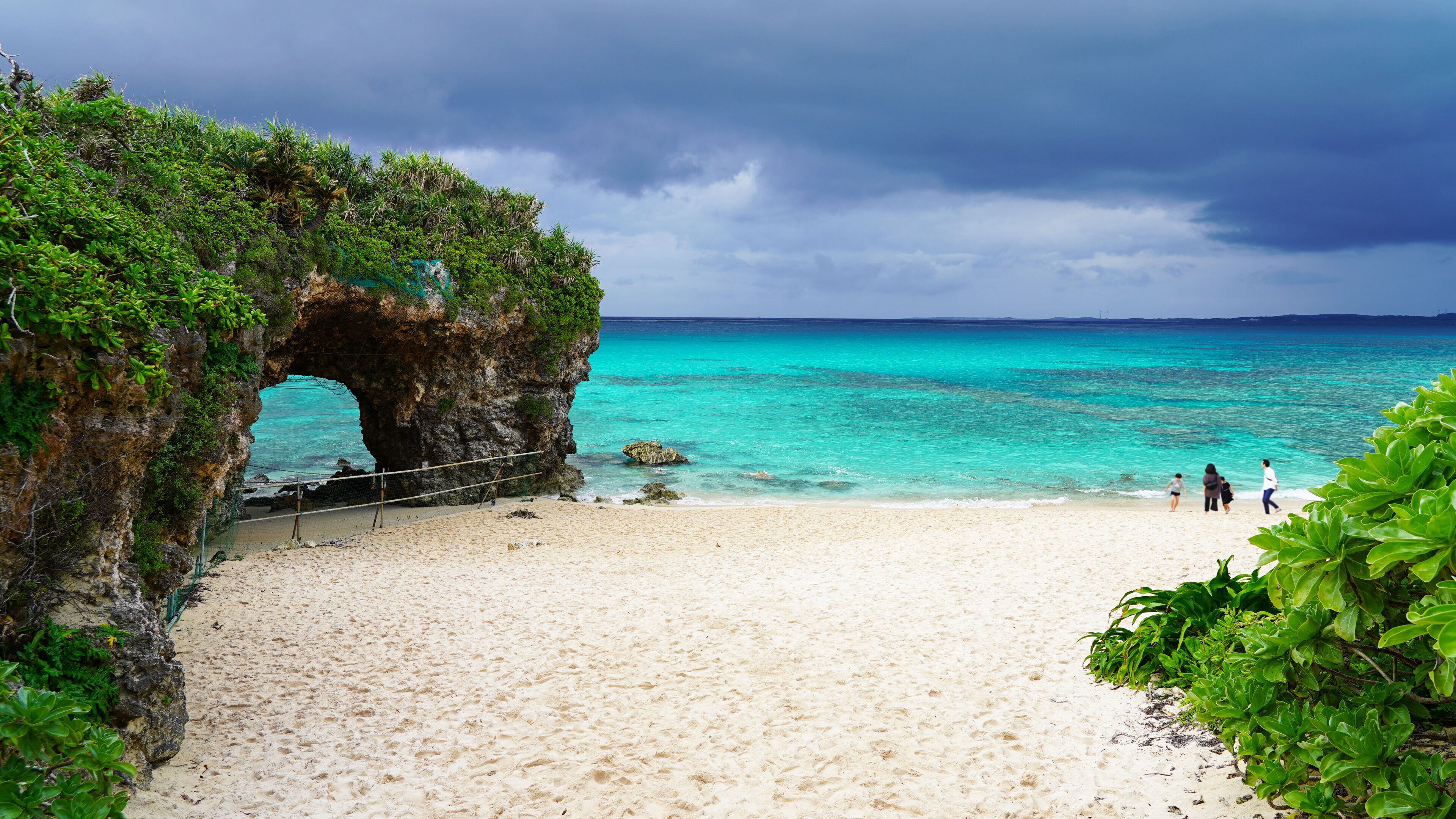 Una playa con un arco natural de roca, aguas turquesas cristalinas y una orilla de arena.