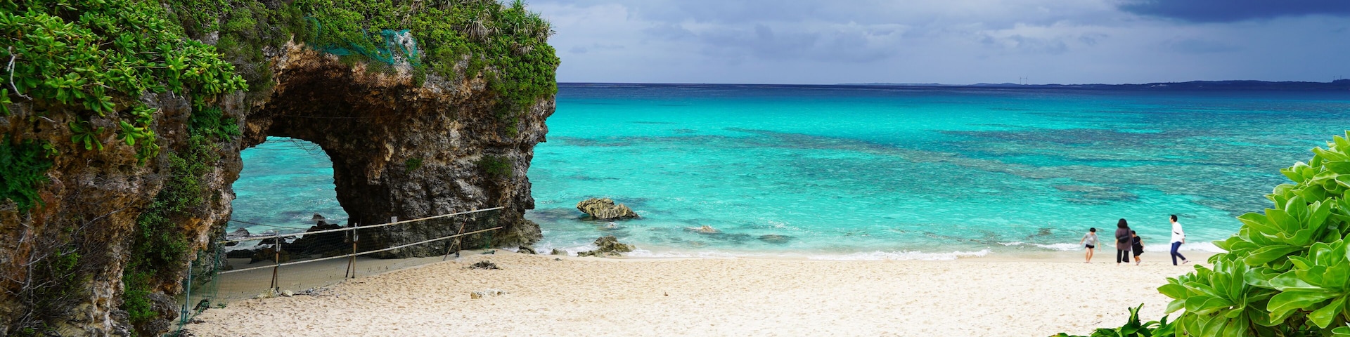 Una playa con un arco natural de roca, aguas turquesas cristalinas y una orilla de arena.