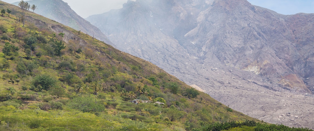 A mountainous landscape with a small house on a grassy hill.