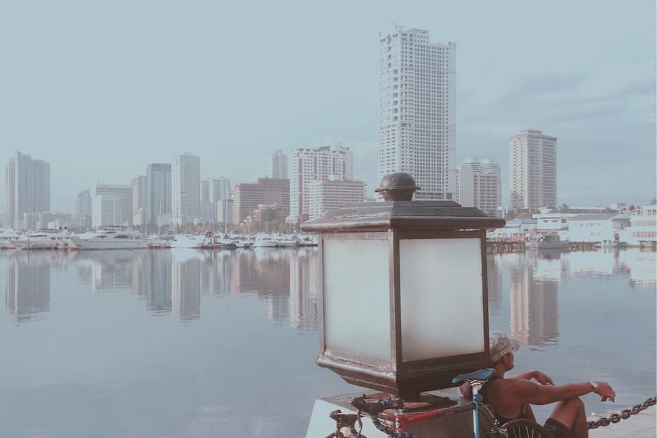 A bicycle parked by a waterfront with a city skyline in the background.