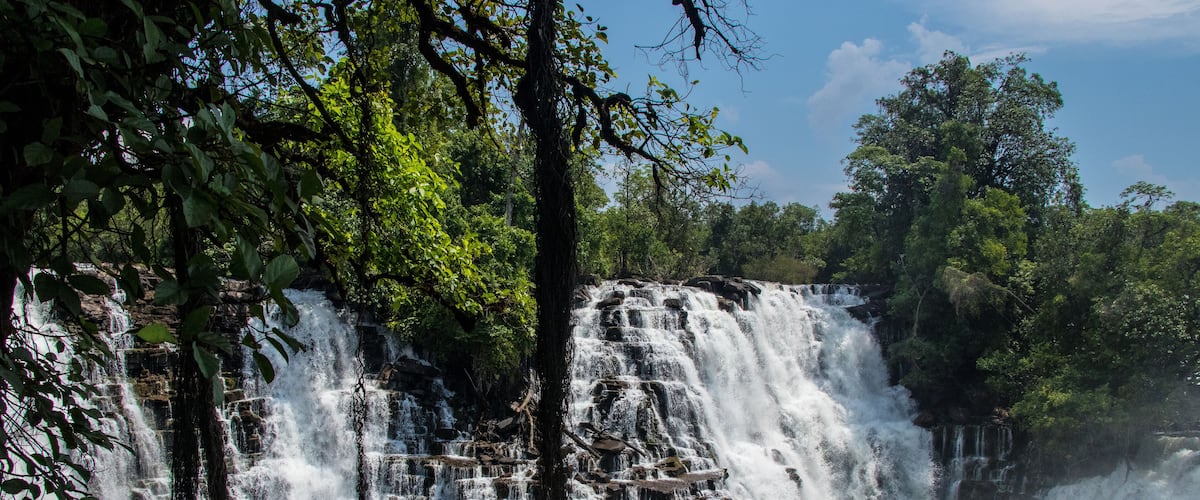 A multi-tiered waterfall surrounded by lush greenery.