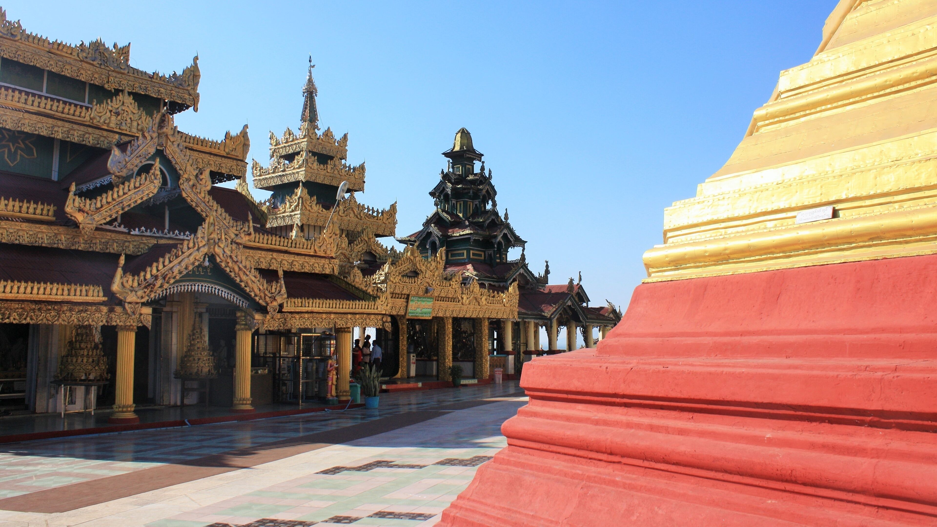 A traditional Thai temple with ornate architecture and a large red stupa.