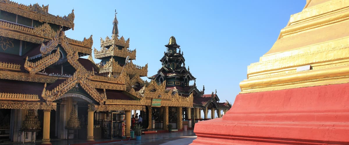 A traditional Thai temple with ornate architecture and a large red stupa.