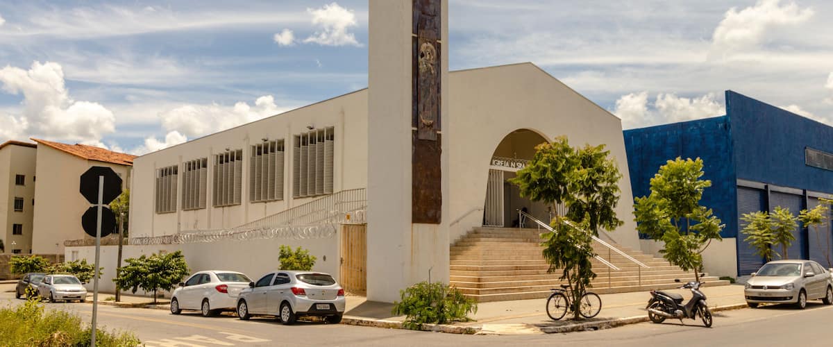A church with a cross, a staircase, and parked cars.