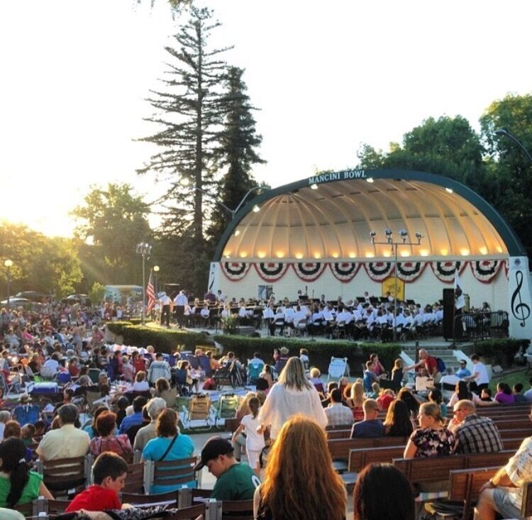 A large outdoor amphitheater with a dome roof, surrounded by a crowd of people.