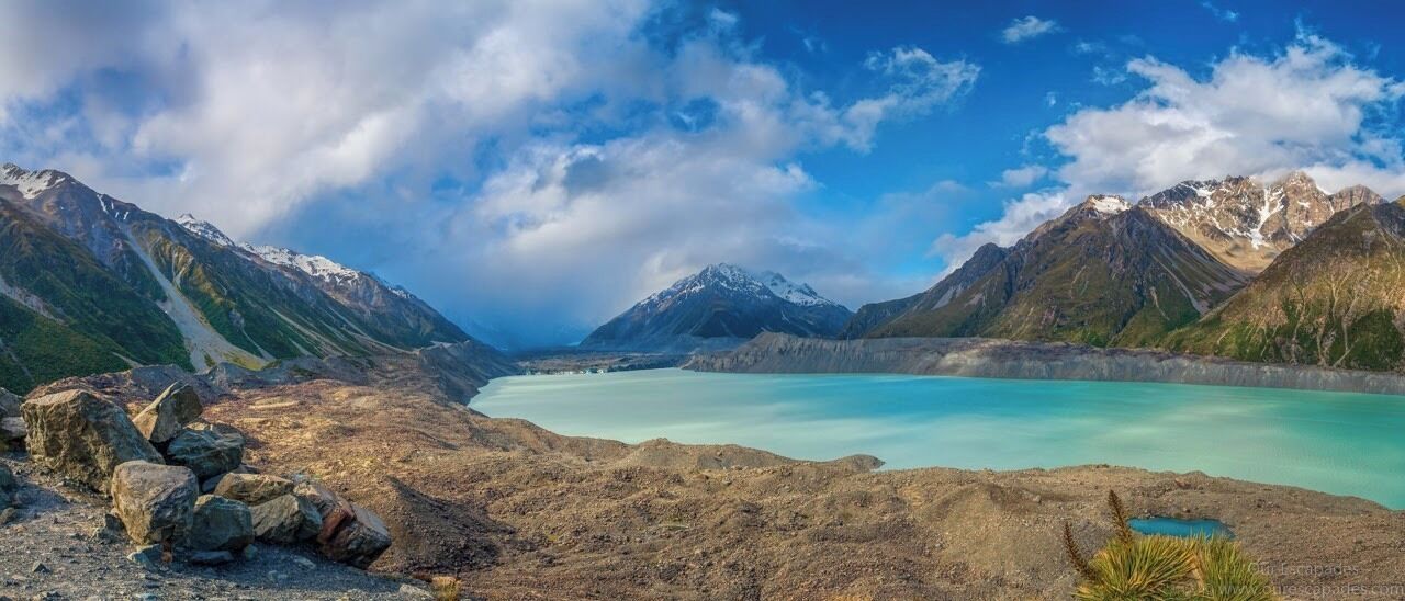 A mountainous landscape with a turquoise lake surrounded by rocky terrain and snow-capped peaks.