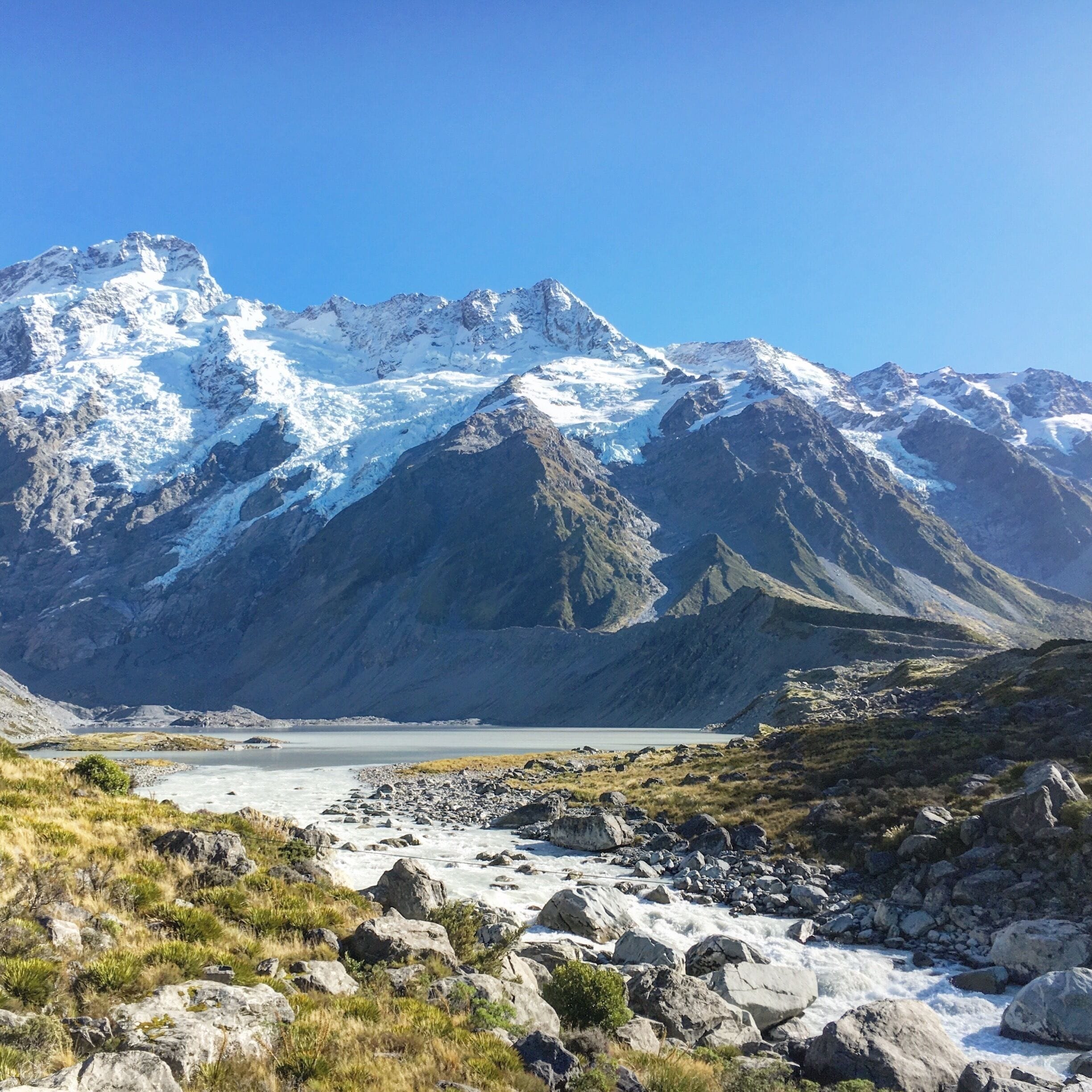 Un paisaje montañoso con un glaciar y un río.