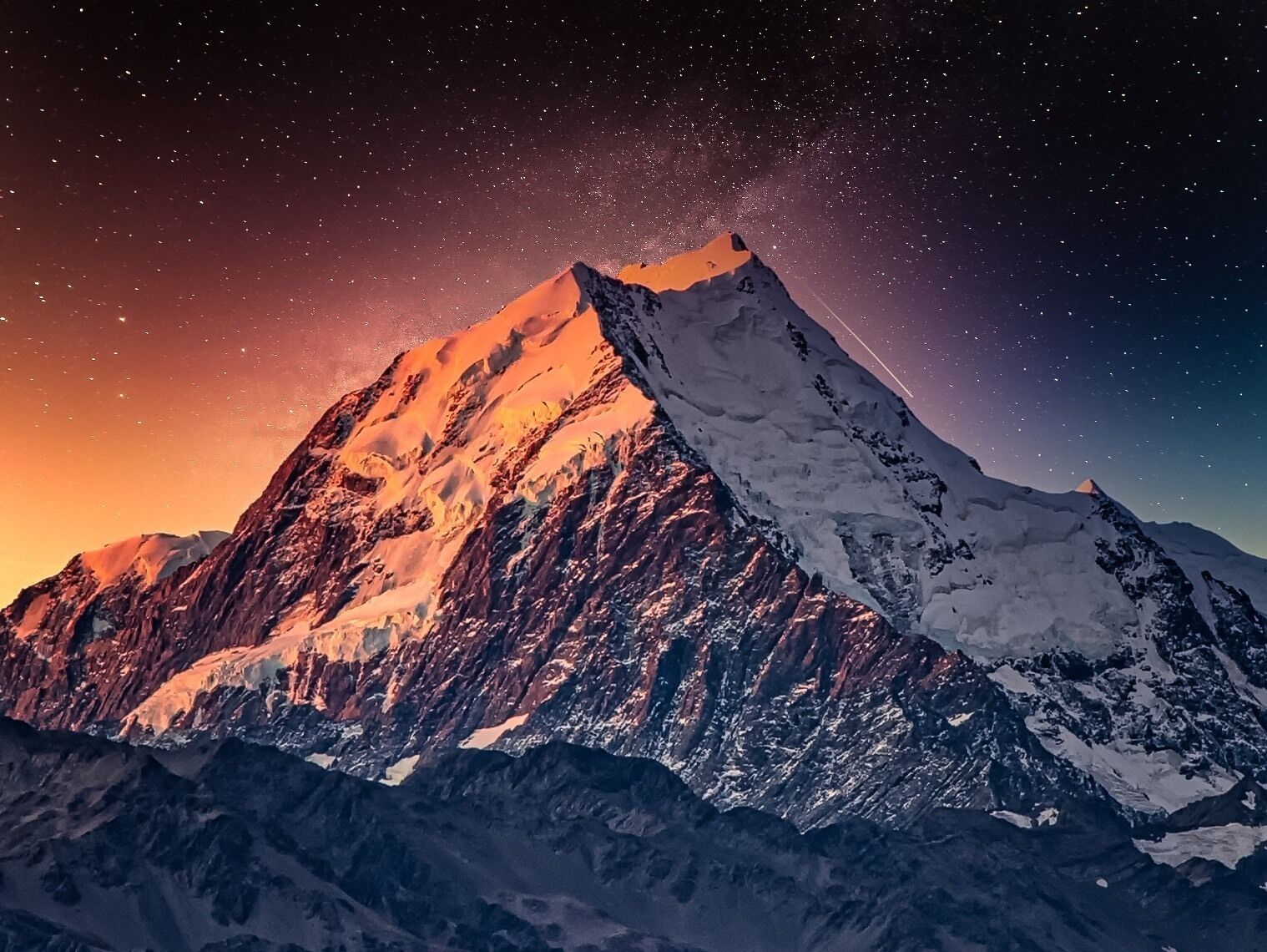 Un pico nevado de montaña bajo un cielo estrellado.