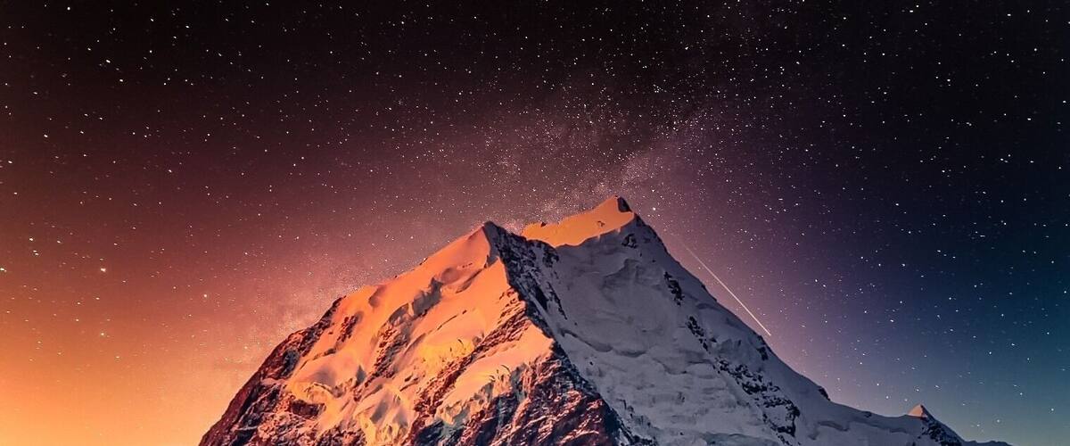 A snow-covered mountain peak under a starry night sky.