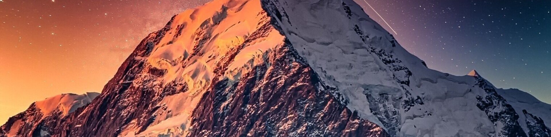 Un pico nevado de montaña bajo un cielo estrellado.