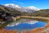 A mountain landscape with a clear lake reflecting the mountains and sky.