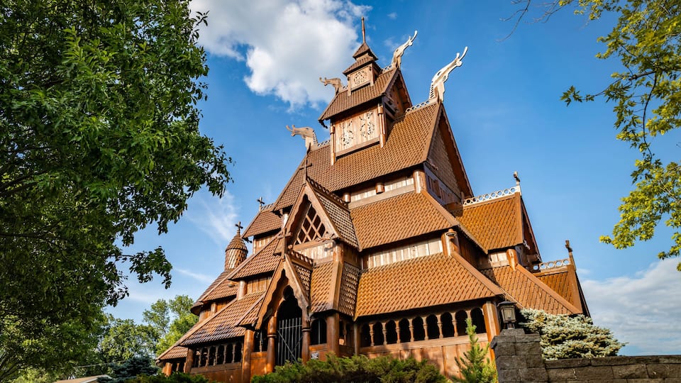 A large, ornate wooden building with steeply pitched roofs and decorative carvings.