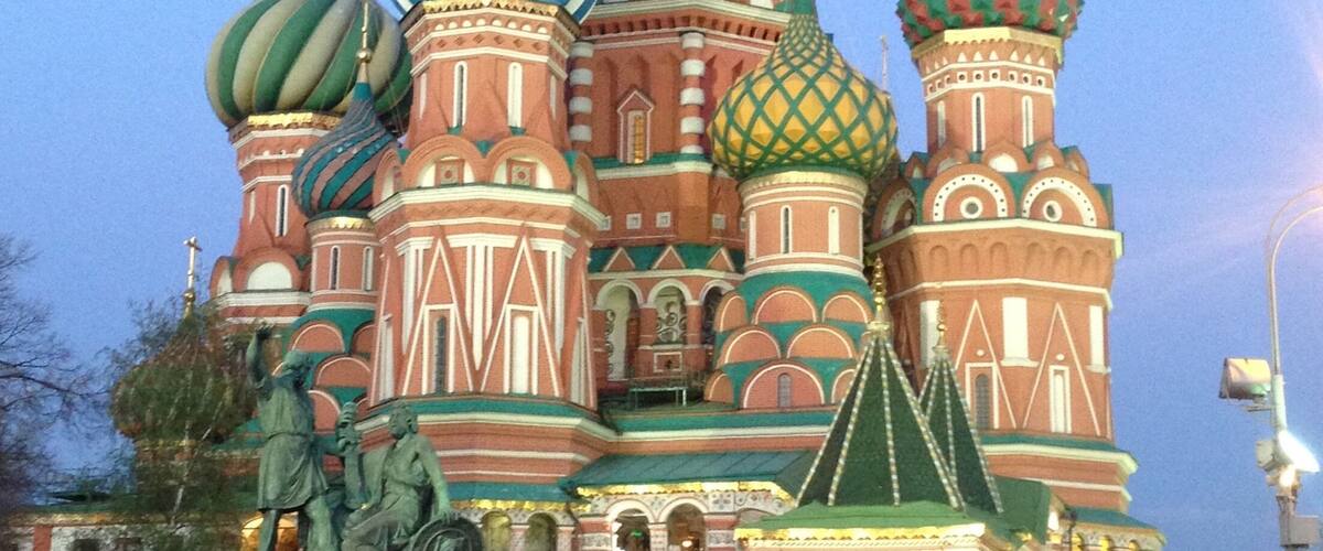 Saint Basil's Cathedral with colorful onion domes and a statue in front.