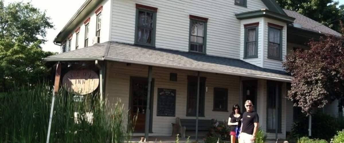 A two-story house with a porch, surrounded by a garden with various plants and a small American flag.