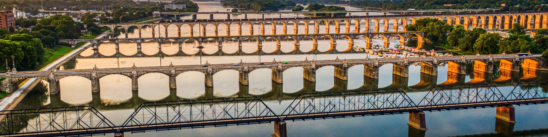 Many bridges over river in sunset, Harrisburg, Pennsylvania, Susquehanna river crossings aerial view, dramatic evening reflection in water, scenic American vista
