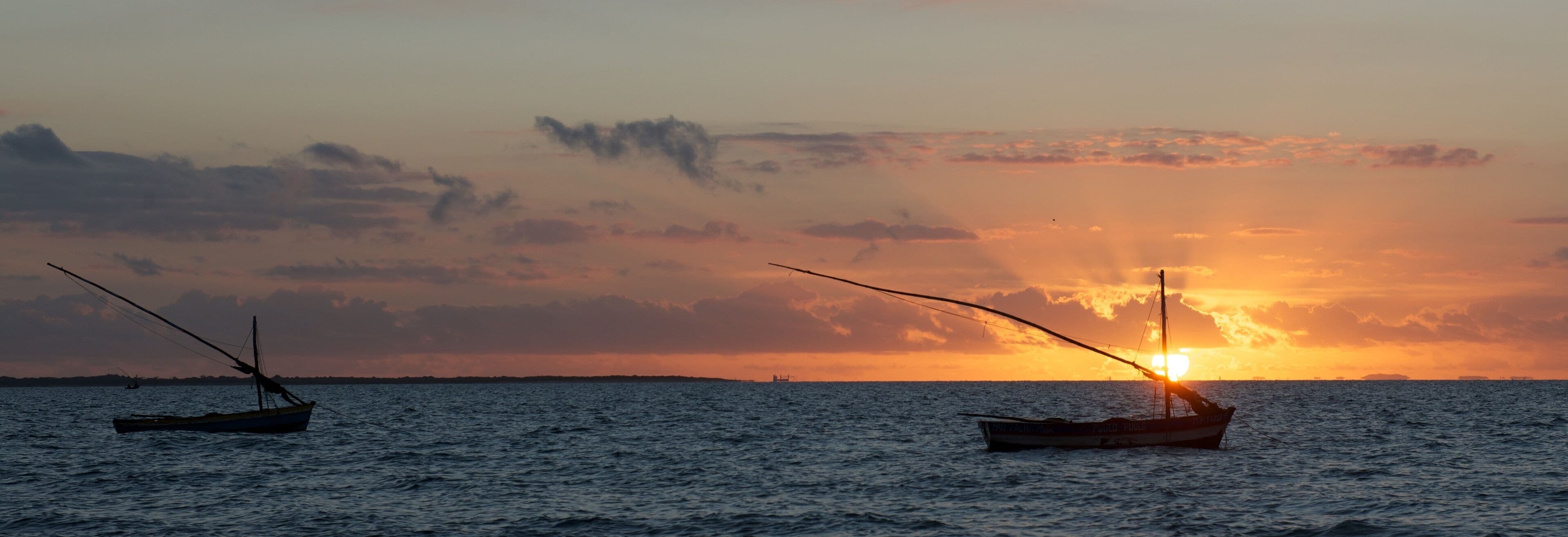Two boats on calm water during sunset.