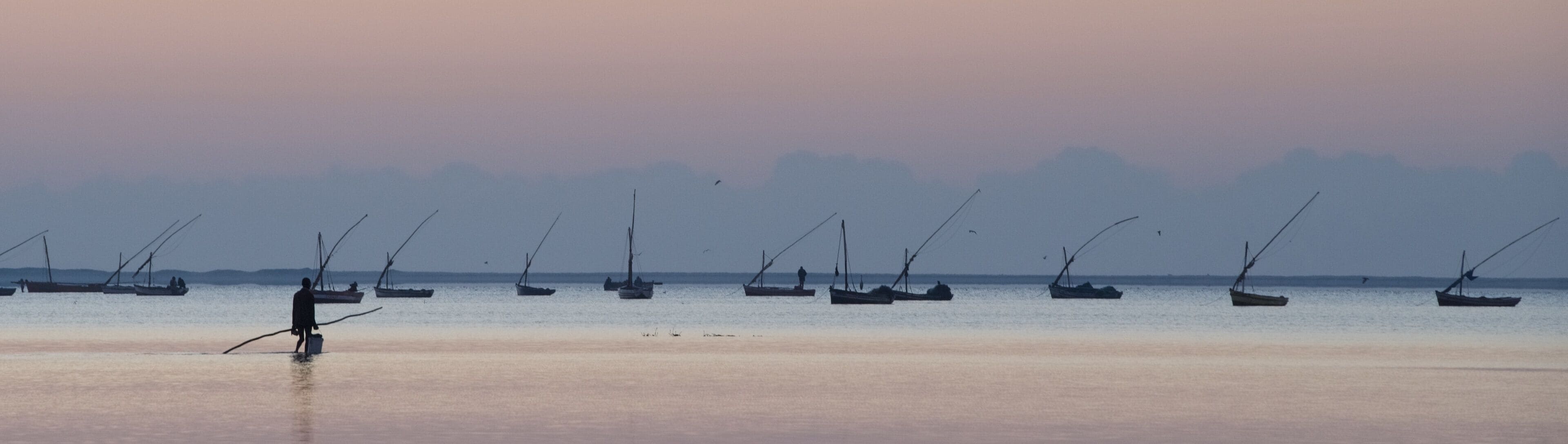 A beach with several fishing boats anchored in the water.