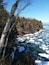 A rocky shoreline with ice floes and birch trees.