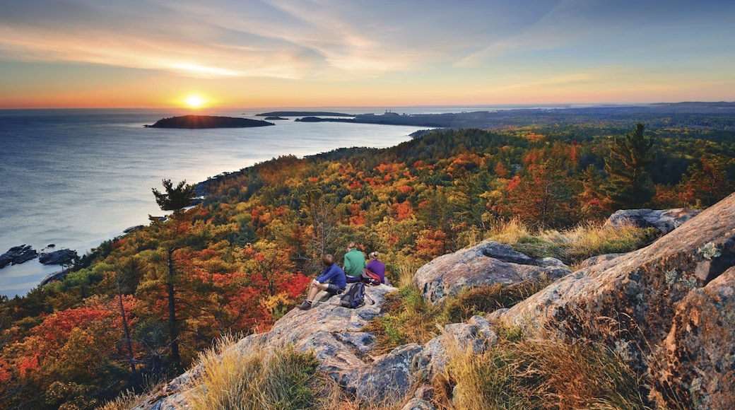 Marquette which includes general coastal views and a sunset as well as a small group of people