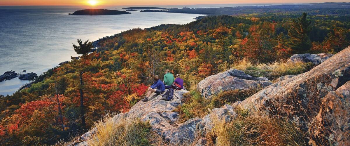 Marquette which includes general coastal views and a sunset as well as a small group of people