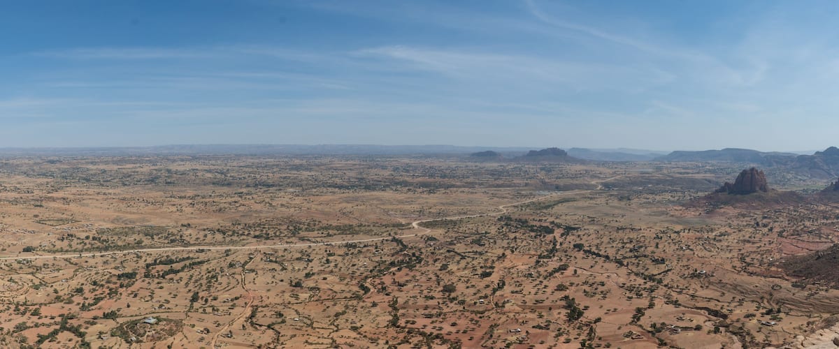 A vast desert landscape with scattered settlements and a prominent rock formation.