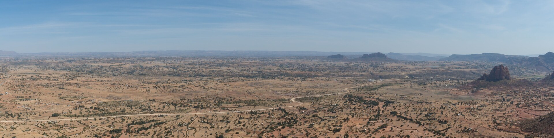 A vast desert landscape with scattered settlements and a prominent rock formation.