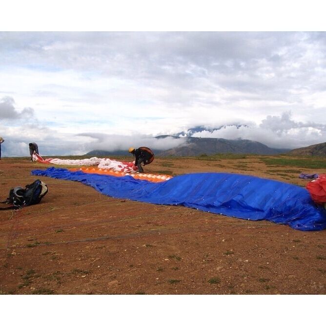 A blue tarp laid out on a dirt field with mountains in the background.