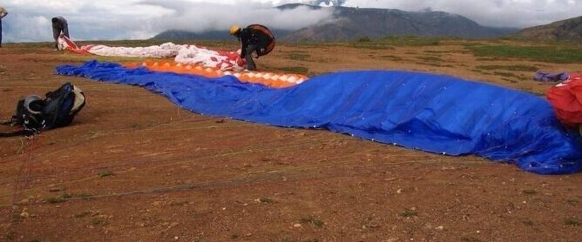 A blue tarp laid out on a dirt field with mountains in the background.