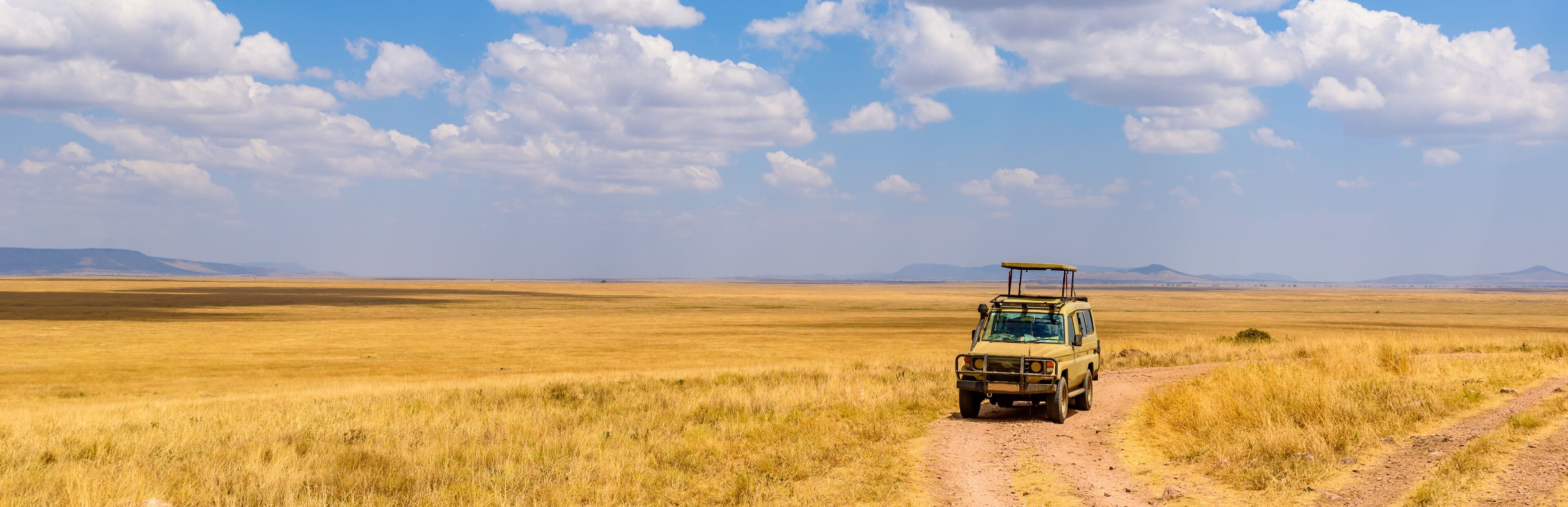 Safari tourists on game drive with Jeep car in Serengeti National Park in beautiful landscape scenery, Tanzania, Africa