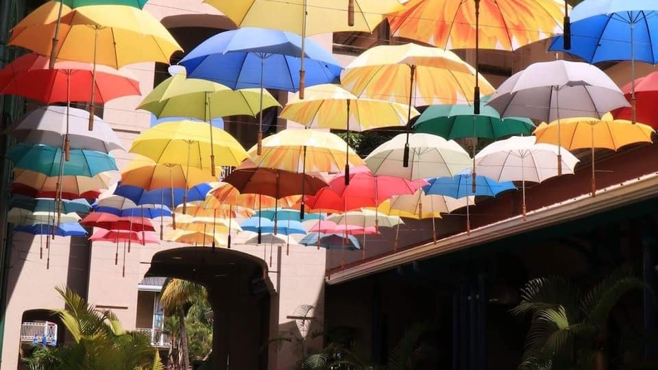 A courtyard with a patterned floor and hanging umbrellas in various colors.
