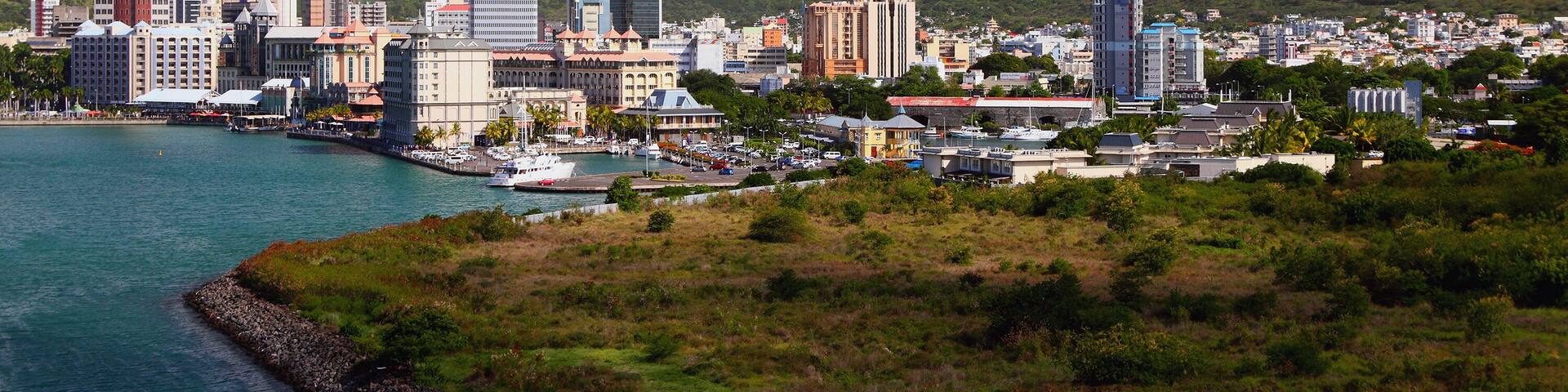 A coastal cityscape with a prominent mountain range in the background.