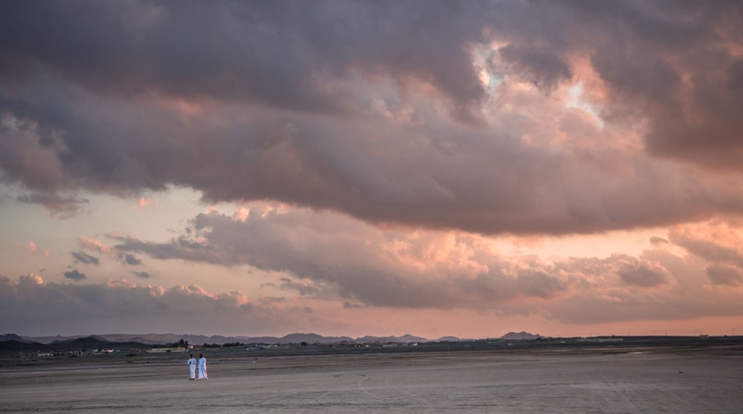 Two young Arabs walking along the beach stranded during sunset on Masirah Island, Oman
