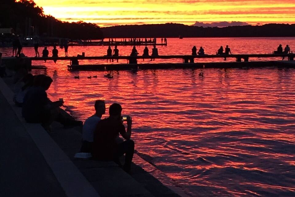 A sunset over a body of water with people sitting on a pier.