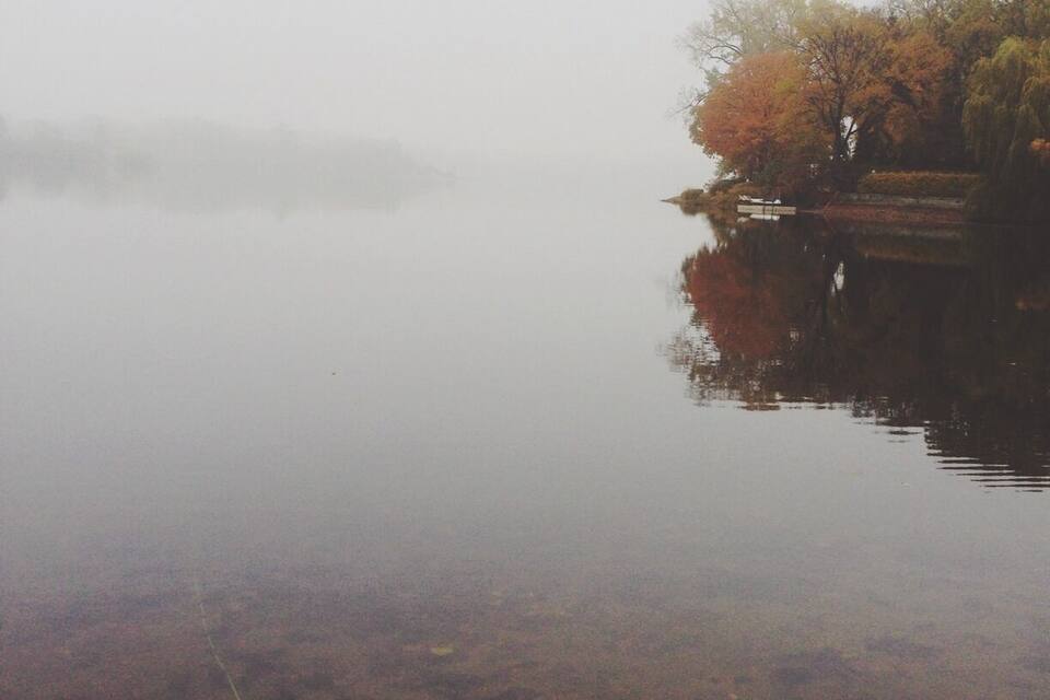 A calm lake with autumn-colored trees reflecting on the water.