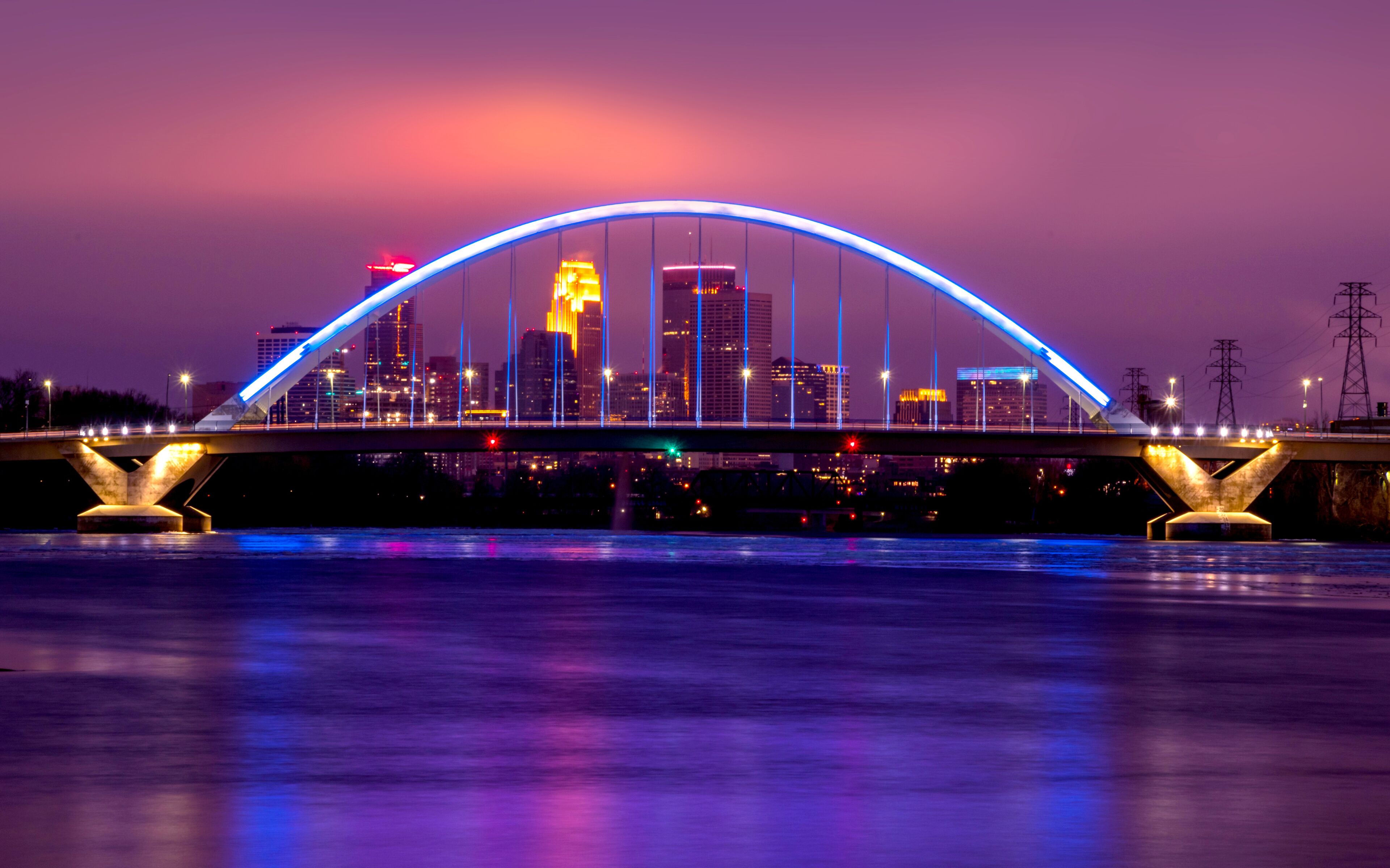 Lowry Avenue Bridge colored blue at dusk with Minneapolis Skyline behind